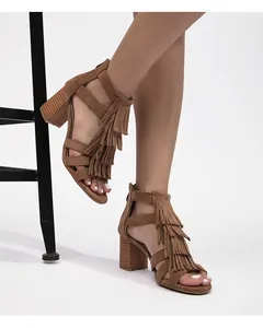 Primer plano de sandalias de ante marrón con flecos y tacón grueso con acabado de madera