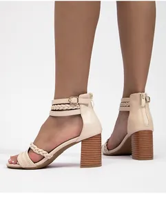 Detalle de sandalias beige con tiras trenzadas y tacón ancho de efecto madera