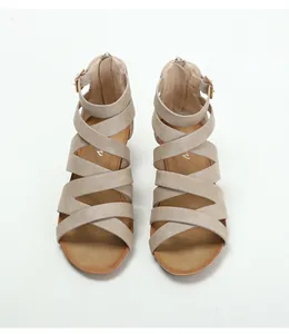 Close-up of beige gladiator sandals featuring crisscross straps and gold buckle detail