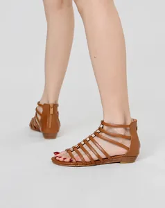 Detailed close-up of brown Roman gladiator sandals with metallic buckles and rear zipper