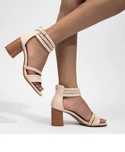 Detalle de sandalias beige con tacón grueso, tiras trenzadas y textura de madera
