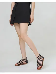 Detail view of black Roman sandals featuring horizontal straps with gold metal accents