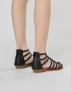 Detail of black multi-strap gladiator sandals with heel zipper and textured flat sole
