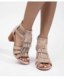 Detalle de sandalias de ante beige con flecos y tacón ancho con textura de grano de madera