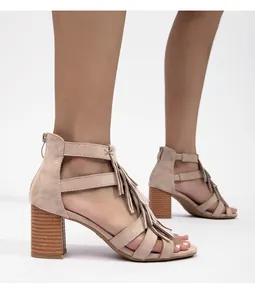 Detalle de sandalias de ante beige con tacón de bloque, flecos y cremallera metálica trasera