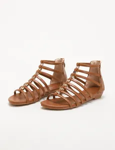 Detail of brown Roman wedge sandals featuring metal accents and a back zipper closure