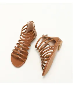 Detail of brown gladiator sandals featuring six gold metal bow buckles and back zipper