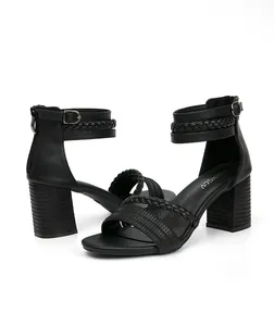 Detalle de sandalias negras de tacón ancho con tiras trenzadas y cremallera trasera