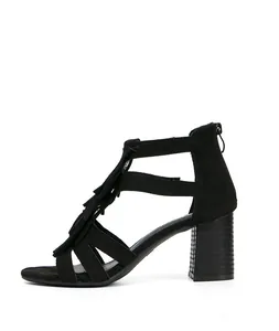 Detalle de sandalias negras con tacón ancho que incluyen flecos elegantes y cremallera