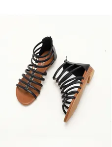 Detail view of black multi-strap gladiator sandals with golden butterfly metal buckles