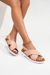 Detalle de sandalias rosas con tiras cruzadas, suela blanca y cadena dorada de tobillo