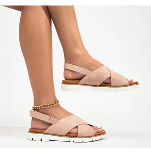 Vista detallada de sandalias planas beige con tiras cruzadas y textura mate suave