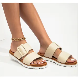 Détail de sandales beiges à doubles brides avec boucle carrée et chaîne dorée