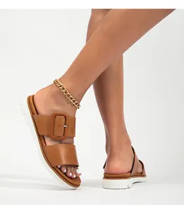Gros plan de sandales plates-formes marron à doubles brides et grandes boucles carrées