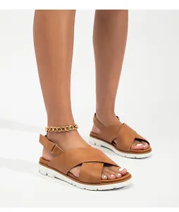 Detalle de sandalias de tiras cruzadas marrones con suela gruesa blanca y hebilla ajustable