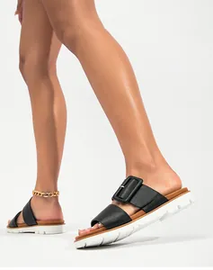 Détail de sandales à plateforme en cuir noir avec boucle carrée et semelle blanche crantée