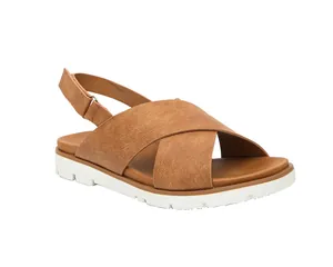 Detalle de sandalias de mujer con correas cruzadas marrones, hebilla y suela de plataforma blanca