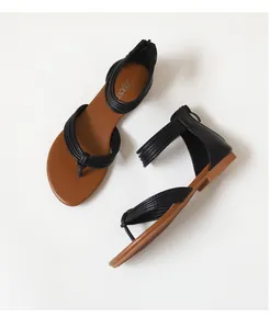 Detailoverzicht van zwarte teensandalen met bruine zool en ritssluiting achter