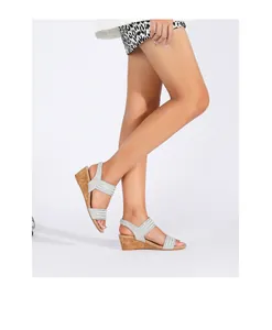 Detalle de sandalias de cuña con purpurina plateada, tiras de strass y tacón de madera