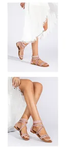 Detail van roze platte sandalen met glinsterende kruisbandjes en een ritssluiting
