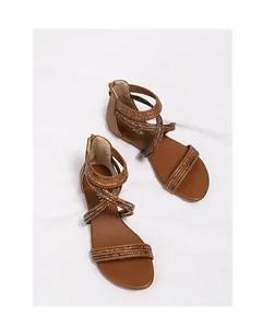 Detail van bruine platte Romeinse sandalen met enkelrits en zachte comfortabele zool