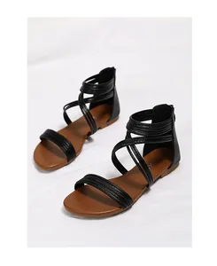 Detail van zwarte Romeinse sandalen met bandjes, rits achteraan en bruine platte zool