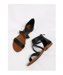 Detail van zwarte Romeinse sandalen met bruine zool en een ritssluiting achteraan