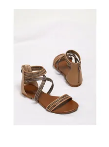 Detail van bruine platte Romeinse sandalen met gevlochten bandjes en ritssluiting achteraan