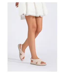 Detail of beige criss-cross strap sandals with adjustable back strap on a model