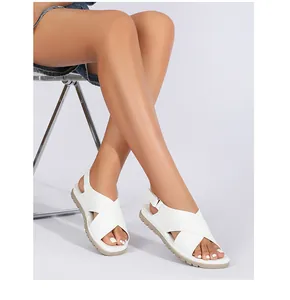 Close-up of white cross-strap summer sandals with an adjustable buckle on model's feet