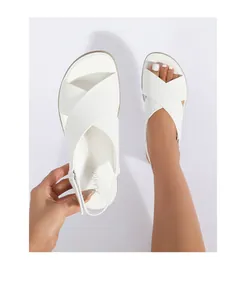 Detailed close-up of white cross-strap flat sandals featuring soft leather and heel straps