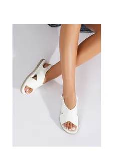 Close-up of women's white platform sandals with crisscross straps and buckle detail