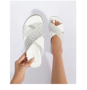Detalle de sandalias veraniegas blancas con correas cruzadas y brillantes pedrería plata