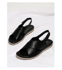 Detail view of black cross-strap sandals with thick beige anti-slip rubber soles
