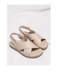 Detail view of beige flat sandals with soft crisscross straps and adjustable heel strap