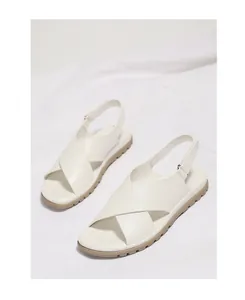 Close-up of white cross-strap sandals with thick khaki non-slip soles and adjustable straps