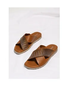 Vista macro de sandalias planas marrones con correas cruzadas adornadas con pedrería
