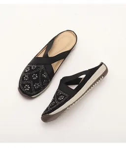 Detail of black slip-on shoes with silver rhinestones and elastic cross straps