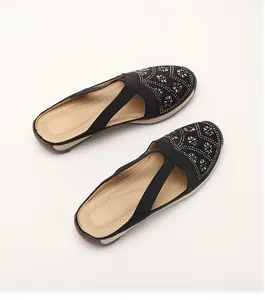 Detail of black slip-on mule with silver rhinestone patterns and elastic cross straps