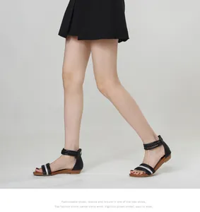 Detail of black wedge sandals featuring woven straps and sparkling rhinestone embellishments