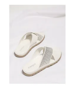 Detalle de sandalias blancas de mujer con correas cruzadas de strass y suelas gruesas