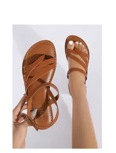 Close-up of brown leather strappy sandals with toe ring and adjustable ankle buckle
