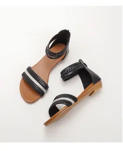Close-up of black sandals with rhinestone detailing, braided straps and back zipper