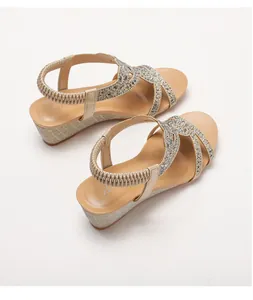 Dettaglio dei sandali con zeppa color champagne con strass e cinturino elastico