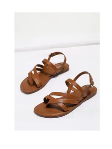 Detailed shot of brown leather gladiator sandals with cross straps and metal buckle closure