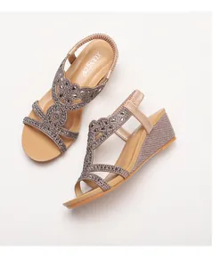 Dettaglio di sandali con zeppa beige con strass grigi scintillanti e cinturino elastico