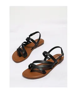 Close-up of black strappy sandals with toe loop and adjustable buckle on white cloth