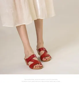 Détail de mules compensées en cuir rouge avec brides asymétriques et motif crocodile