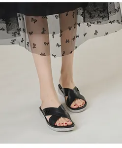 Close-up of black platform wedge sandals featuring cross straps and metallic buckle detail
