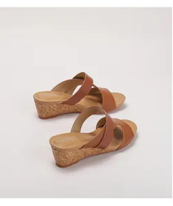 Détail de sandales compensées marron avec brides croisées et semelle en texture liège